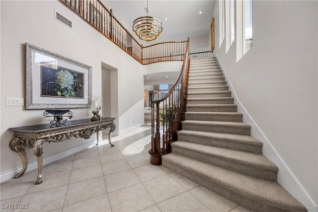 staircase with a towering ceiling, baseboards, tile patterned flooring, and healthy amount of natural light