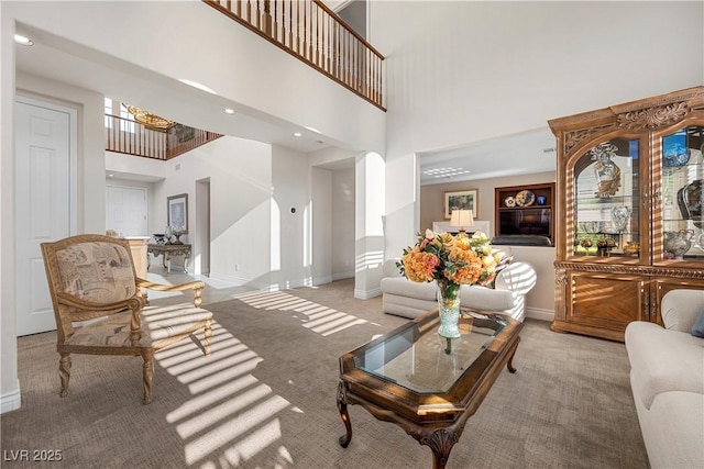carpeted living room featuring a high ceiling, baseboards, a chandelier, and recessed lighting