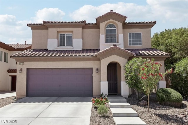 mediterranean / spanish home with an attached garage, stucco siding, a tiled roof, and concrete driveway
