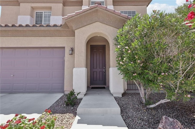 doorway to property with a garage and stucco siding
