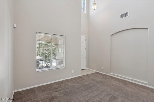 interior space featuring a high ceiling, visible vents, baseboards, and carpet