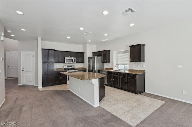 kitchen with visible vents, light colored carpet, a kitchen island, and stainless steel appliances