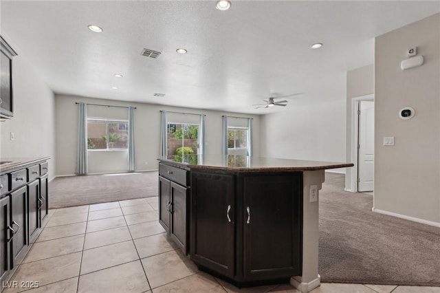 kitchen featuring a kitchen island, a ceiling fan, baseboards, light carpet, and recessed lighting