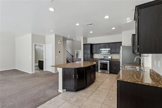 kitchen with light tile patterned flooring, light carpet, a sink, a center island, and stainless steel appliances