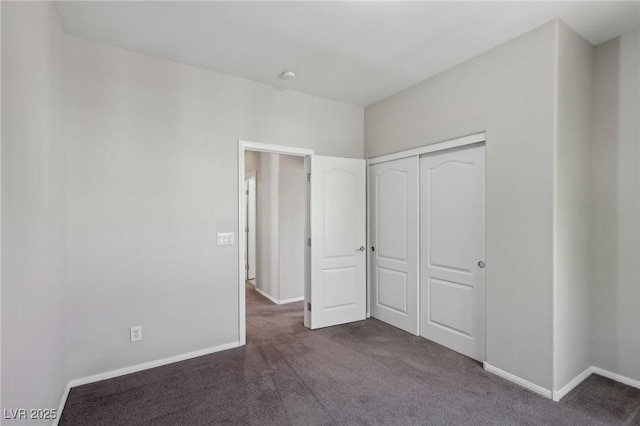 unfurnished bedroom featuring a closet, baseboards, and dark colored carpet