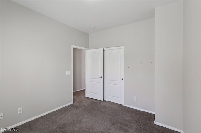 unfurnished bedroom featuring baseboards, a closet, and dark carpet