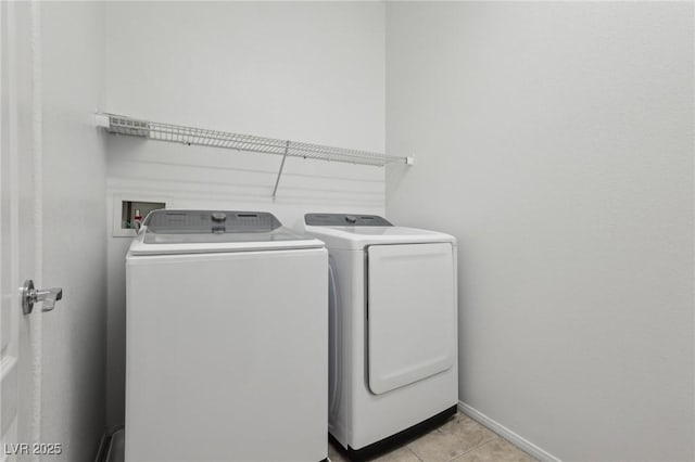 clothes washing area featuring baseboards, laundry area, light tile patterned flooring, and washing machine and clothes dryer