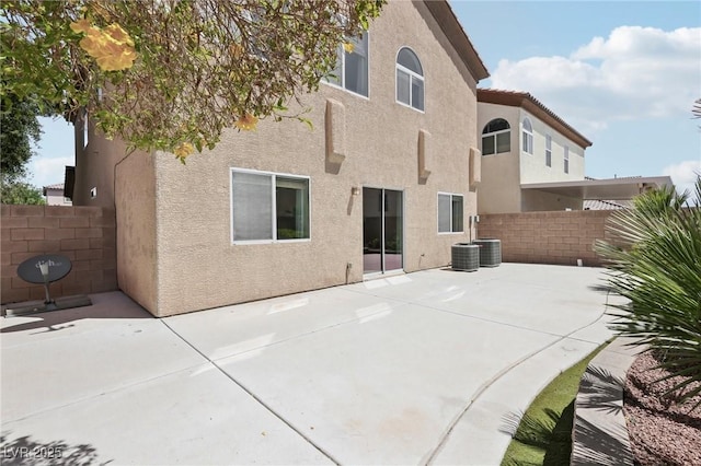 rear view of house featuring a patio, fence, and stucco siding