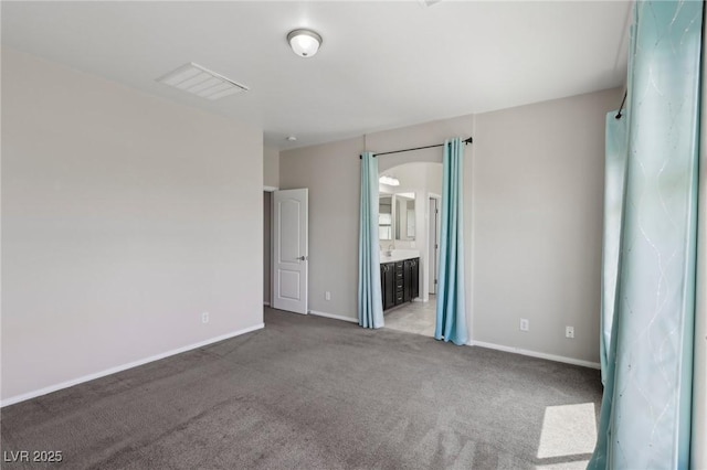 unfurnished bedroom featuring baseboards, carpet, ensuite bath, and visible vents