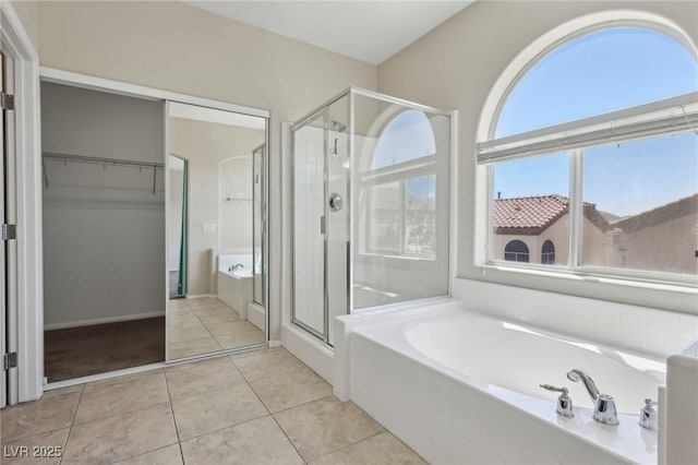 full bathroom with tile patterned flooring, a walk in closet, a garden tub, and a shower stall