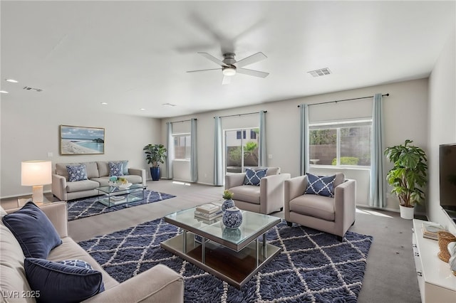 living room with carpet flooring, a ceiling fan, visible vents, and a healthy amount of sunlight