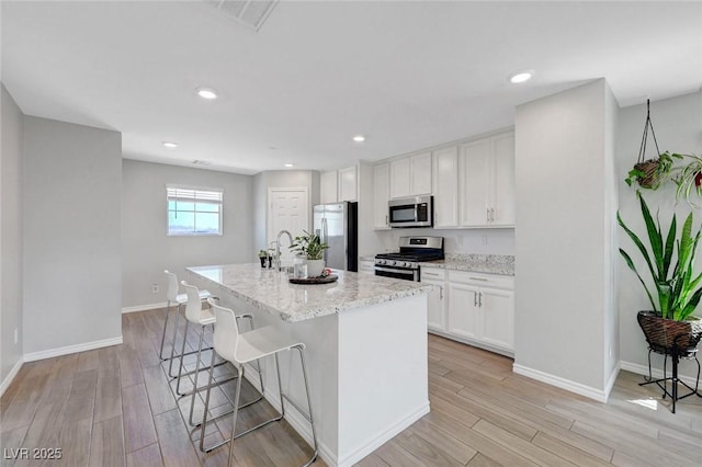 96 Campbelltown Ave, Henderson, NV 89015 - kitchen featuring appliances with stainless steel finishes, white cabinets, a breakfast bar area, and light wood-style flooring