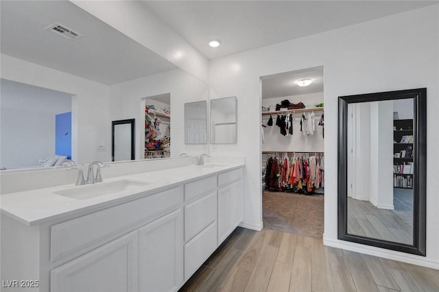 96 Campbelltown Ave, Henderson, NV 89015 - full bathroom featuring visible vents, double vanity, wood finished floors, a walk in closet, and a sink
