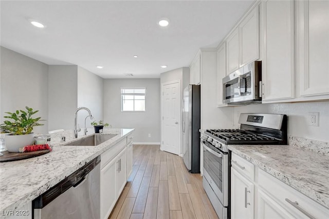96 Campbelltown Ave, Henderson, NV 89015 - kitchen with white cabinets, appliances with stainless steel finishes, a sink, baseboards, and light wood-type flooring