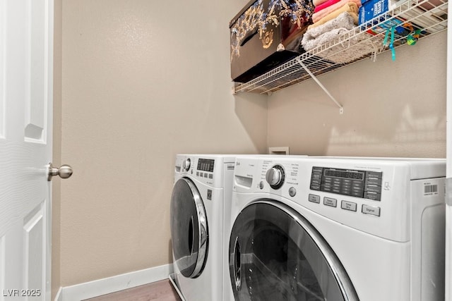 clothes washing area featuring laundry area, baseboards, washing machine and dryer, and wood finished floors
