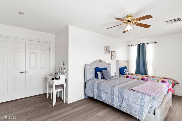 bedroom featuring a ceiling fan, baseboards, visible vents, and wood finished floors