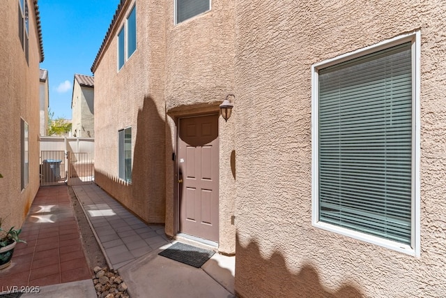 property entrance with fence and stucco siding