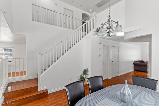 dining area with stairway, a high ceiling, and wood finished floors