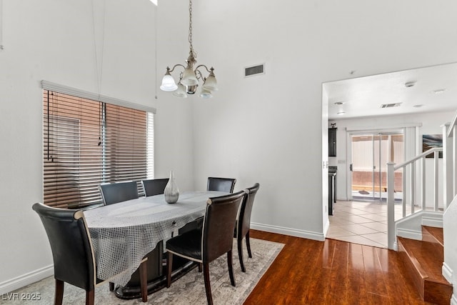 dining space featuring an inviting chandelier, baseboards, wood finished floors, and visible vents