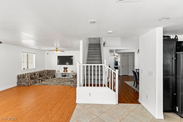 interior space with baseboards, ceiling fan, light tile patterned flooring, and stairway