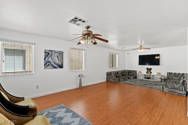 living room with baseboards, ceiling fan, wood finished floors, and visible vents