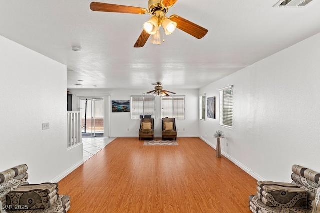 unfurnished living room featuring baseboards, ceiling fan, light wood-style flooring, and visible vents