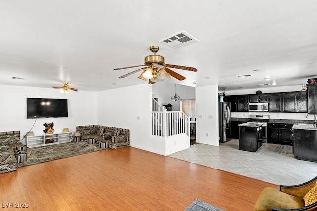 living room featuring visible vents, stairs, ceiling fan, and light wood-style floors