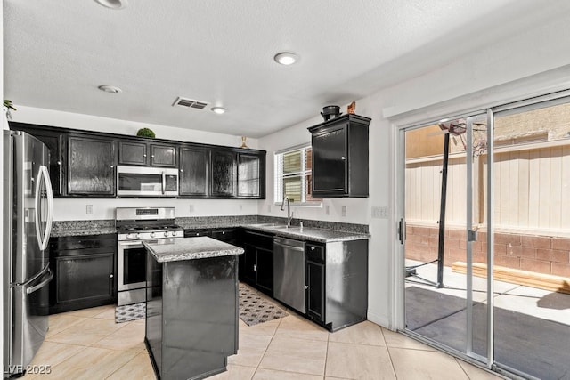kitchen with dark cabinetry, appliances with stainless steel finishes, a sink, and visible vents