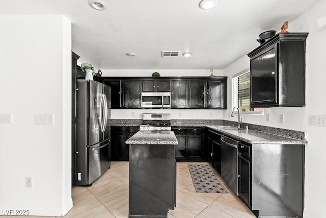 kitchen featuring dark cabinets, a sink, appliances with stainless steel finishes, and visible vents