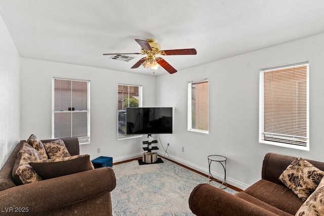 carpeted living area featuring visible vents, baseboards, and ceiling fan