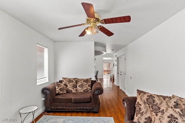 living area featuring baseboards, a ceiling fan, and wood finished floors
