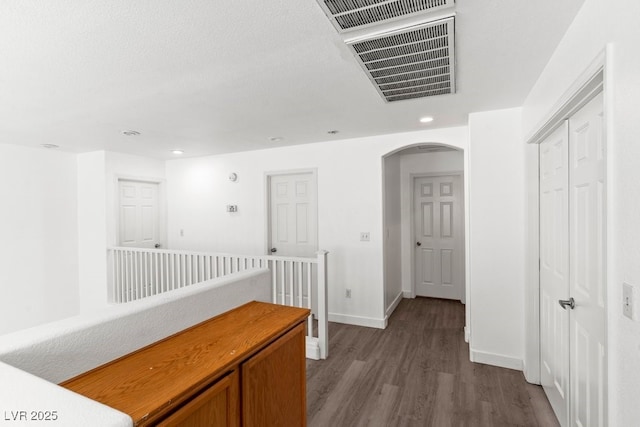 hallway with visible vents, arched walkways, dark wood finished floors, baseboards, and recessed lighting