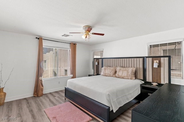 bedroom with a ceiling fan, baseboards, visible vents, and wood finished floors