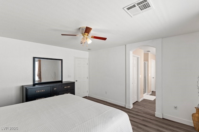 bedroom featuring visible vents, baseboards, ceiling fan, dark wood-type flooring, and arched walkways
