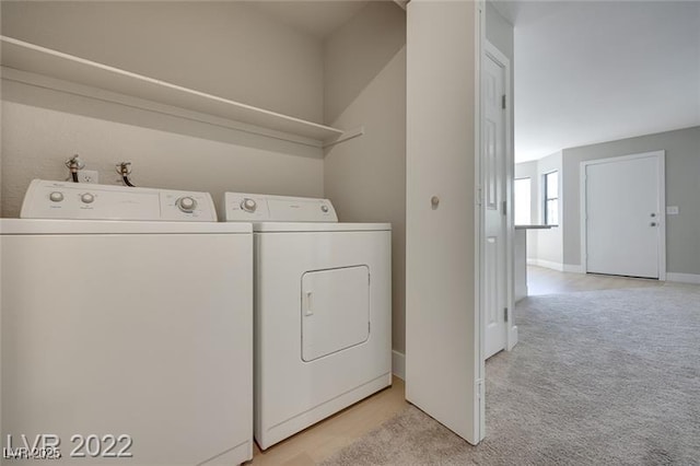 clothes washing area featuring independent washer and dryer, laundry area, light colored carpet, and baseboards