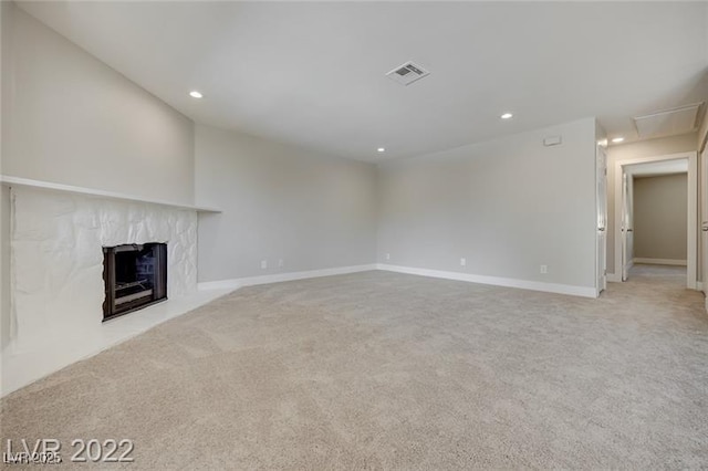 unfurnished living room with recessed lighting, light colored carpet, visible vents, and a high end fireplace