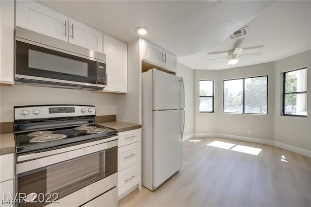 kitchen with white cabinets, stainless steel appliances, baseboards, light wood-type flooring, and visible vents