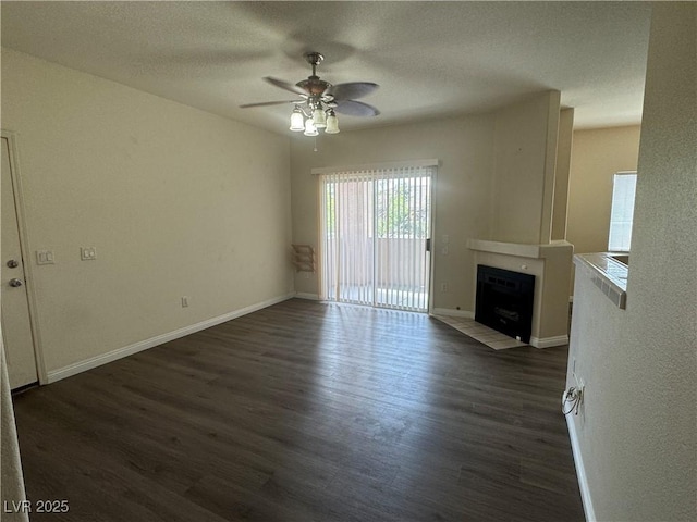 1050 E Cactus Ave Unit 2110, Las Vegas, NV 89183 - unfurnished living room featuring a fireplace with flush hearth, a ceiling fan, dark wood finished floors, baseboards, and a textured ceiling