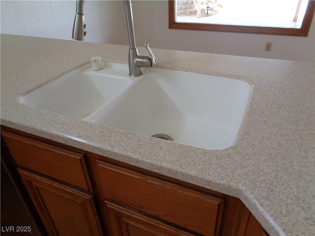 interior details featuring a sink, light countertops, and brown cabinets