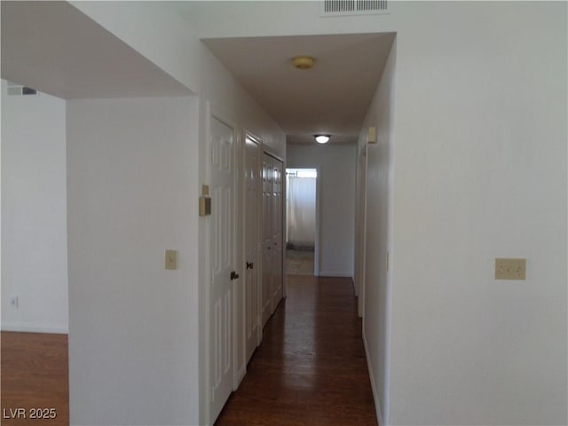 hall with baseboards, visible vents, and wood finished floors