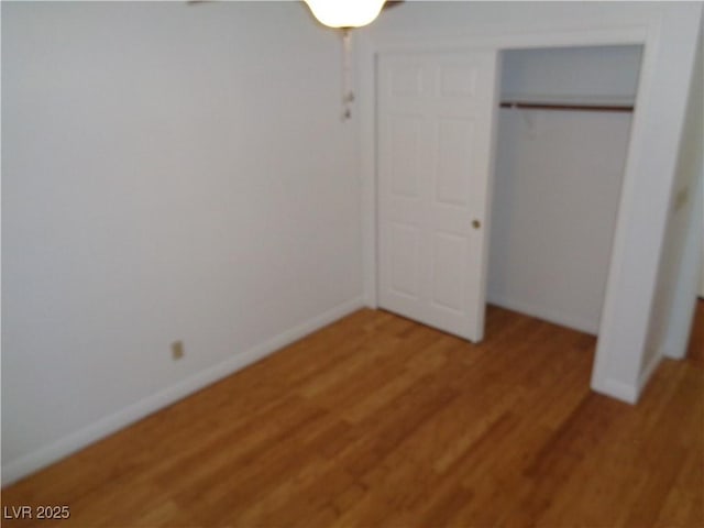 unfurnished bedroom with baseboards, a closet, and light wood finished floors