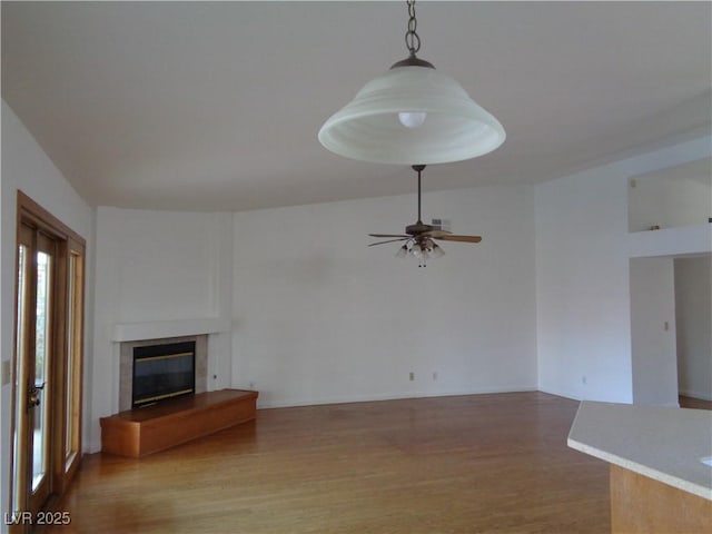 unfurnished living room with ceiling fan, a fireplace, and light wood-style flooring