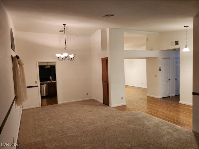 unfurnished room featuring carpet floors, visible vents, high vaulted ceiling, and an inviting chandelier