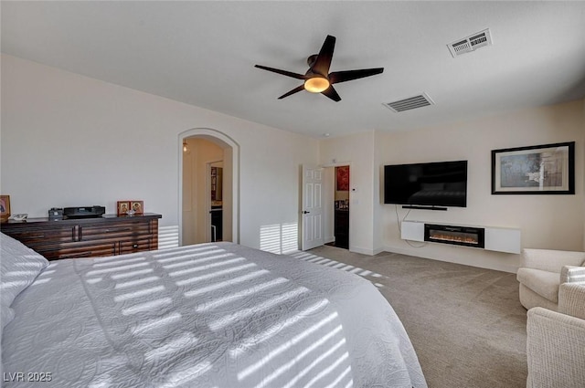 bedroom featuring arched walkways, ceiling fan, carpet, and visible vents