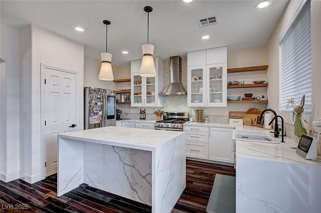 kitchen with visible vents, open shelves, dark wood-style flooring, wall chimney exhaust hood, and stainless steel appliances