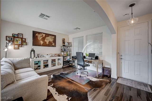 office space with visible vents, arched walkways, and dark wood-style floors