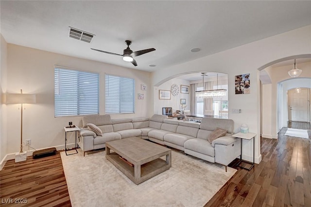 living area with visible vents, arched walkways, baseboards, and a ceiling fan