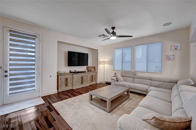 living room with dark wood-type flooring, a ceiling fan, baseboards, and visible vents