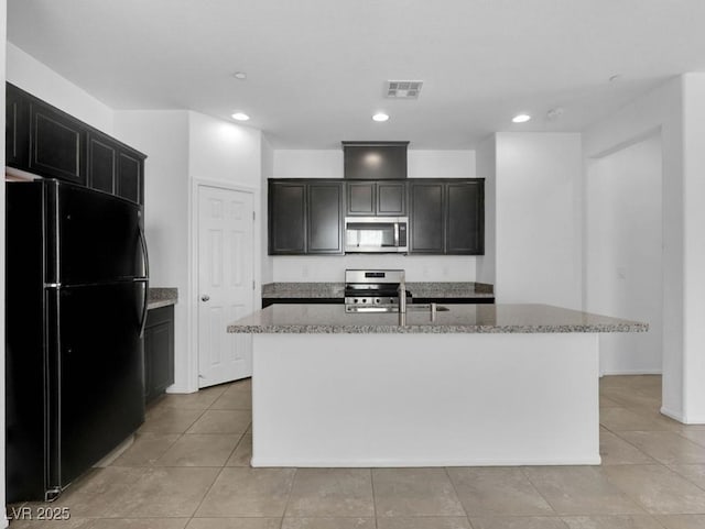 1063 Upper Springs St, Henderson, NV 89002 - kitchen with stainless steel appliances, light stone counters, a center island with sink, light tile patterned floors, and recessed lighting