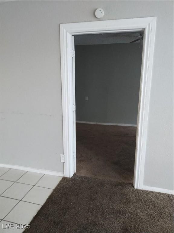 hallway featuring light colored carpet and baseboards